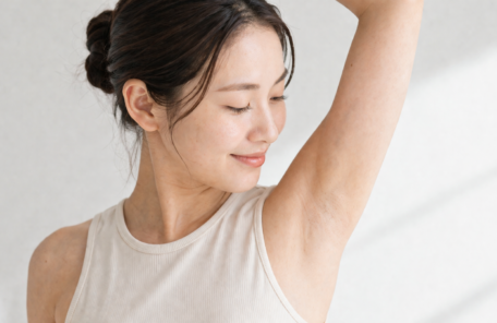 片腕を上げて脇を確認する女性