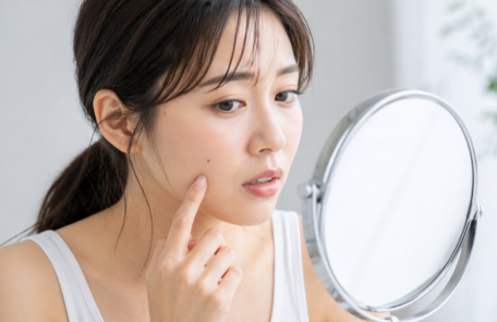 顔のほくろを鏡で確認する女性