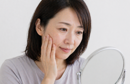 顔のしわ・たるみを気にして鏡を見る女性