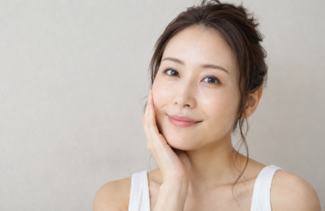 自分の頬を触って微笑む女性